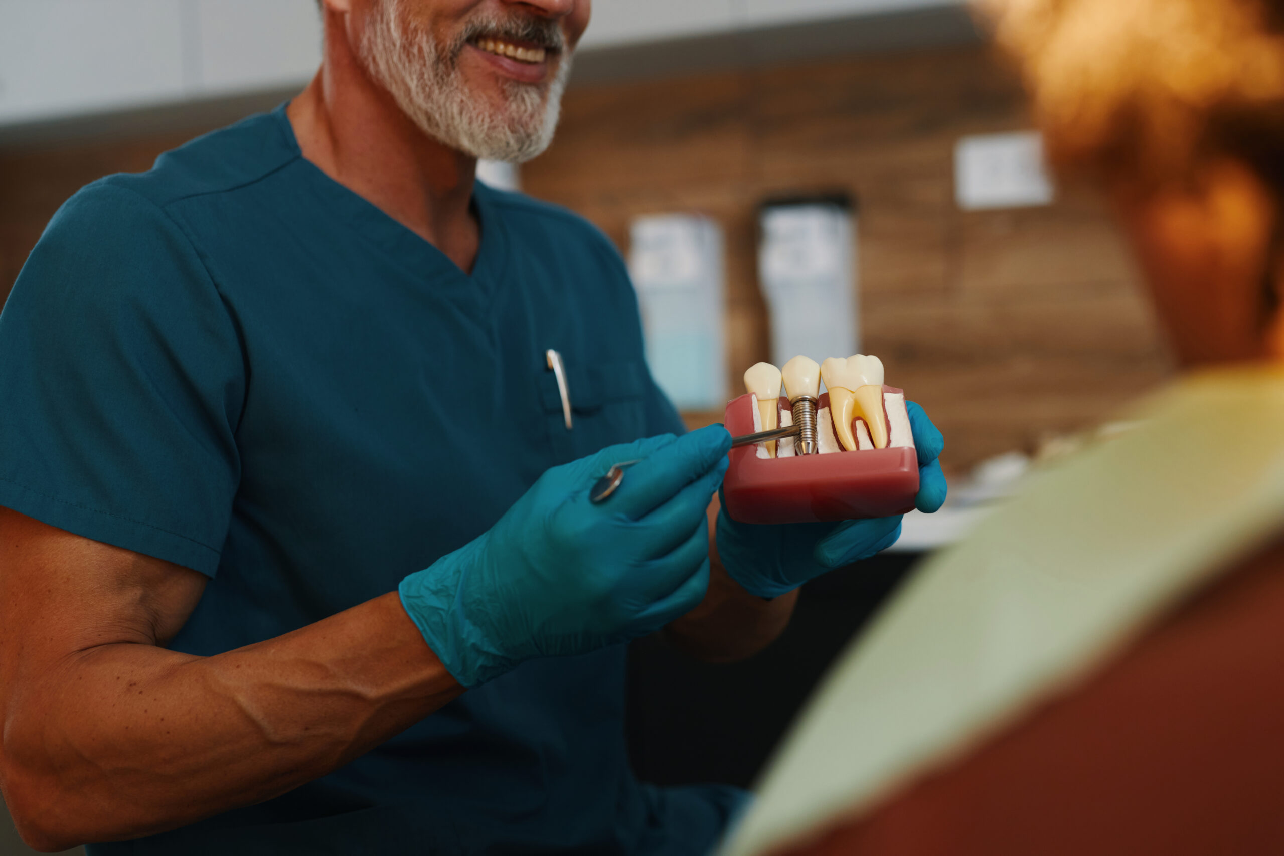 Dentist explaining a dental implant model to a patient during a consultation in a modern dental office
